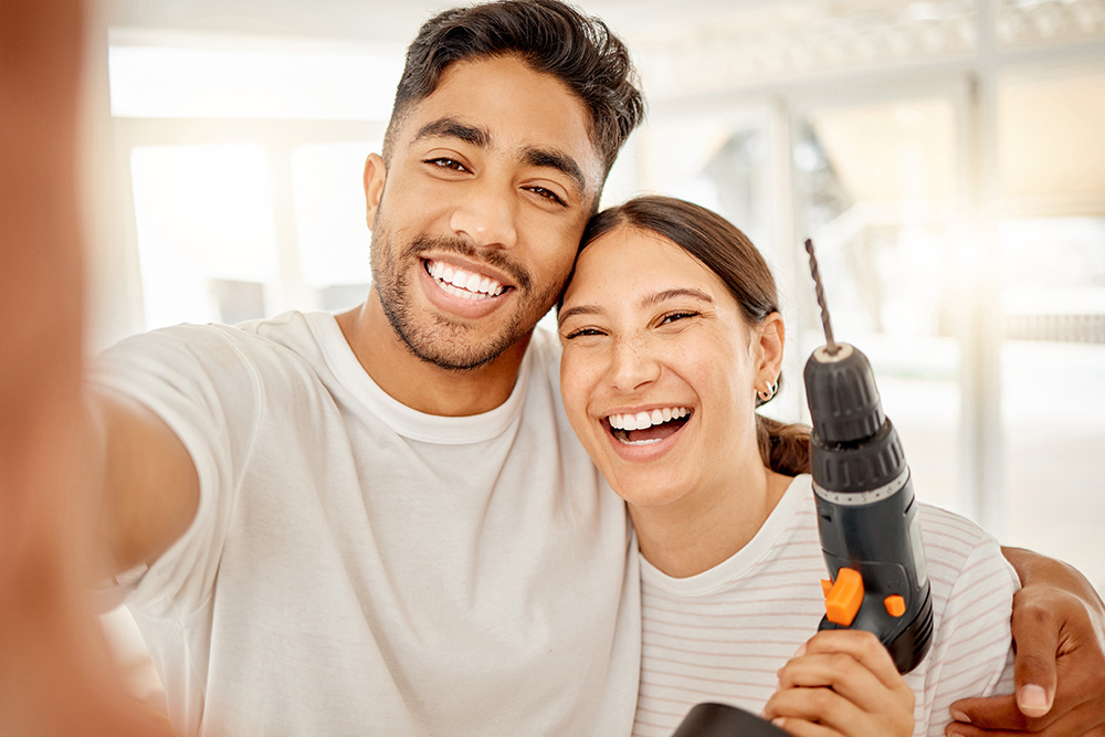 Happy couple holding a drill working on a home improvement.