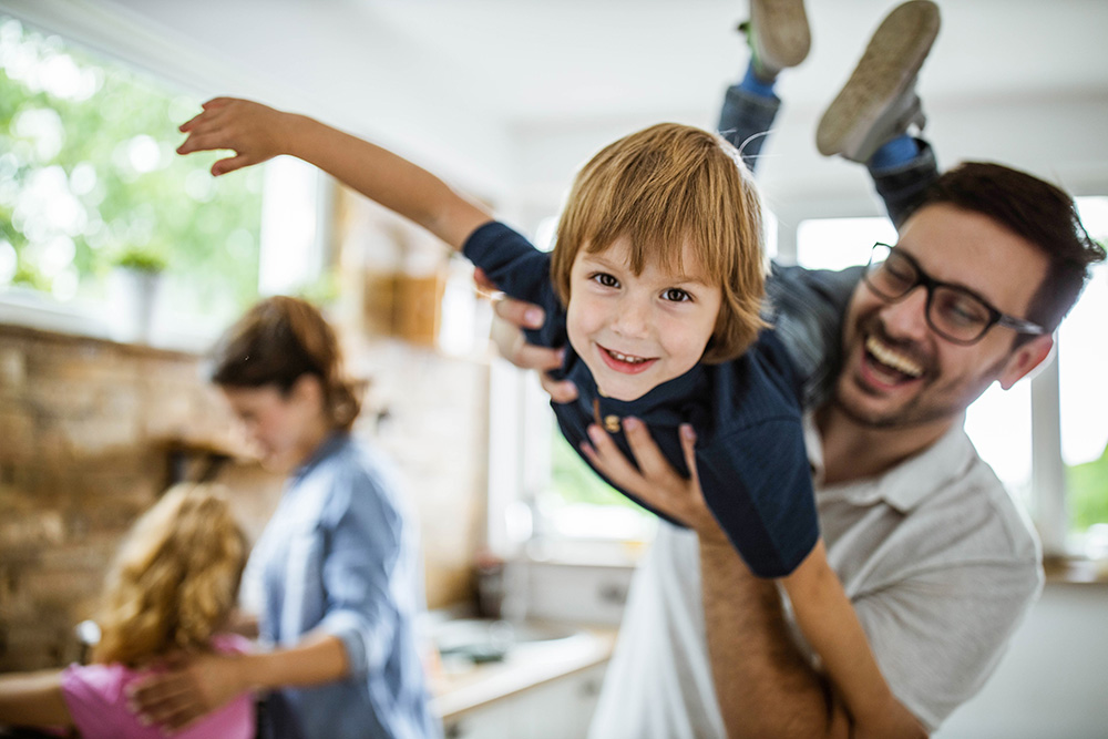 Smiling boy being held by his father.