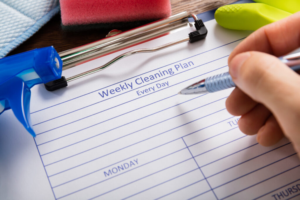 National Get Organized Month. Person writing a cleaning schedule on a pad of paper.