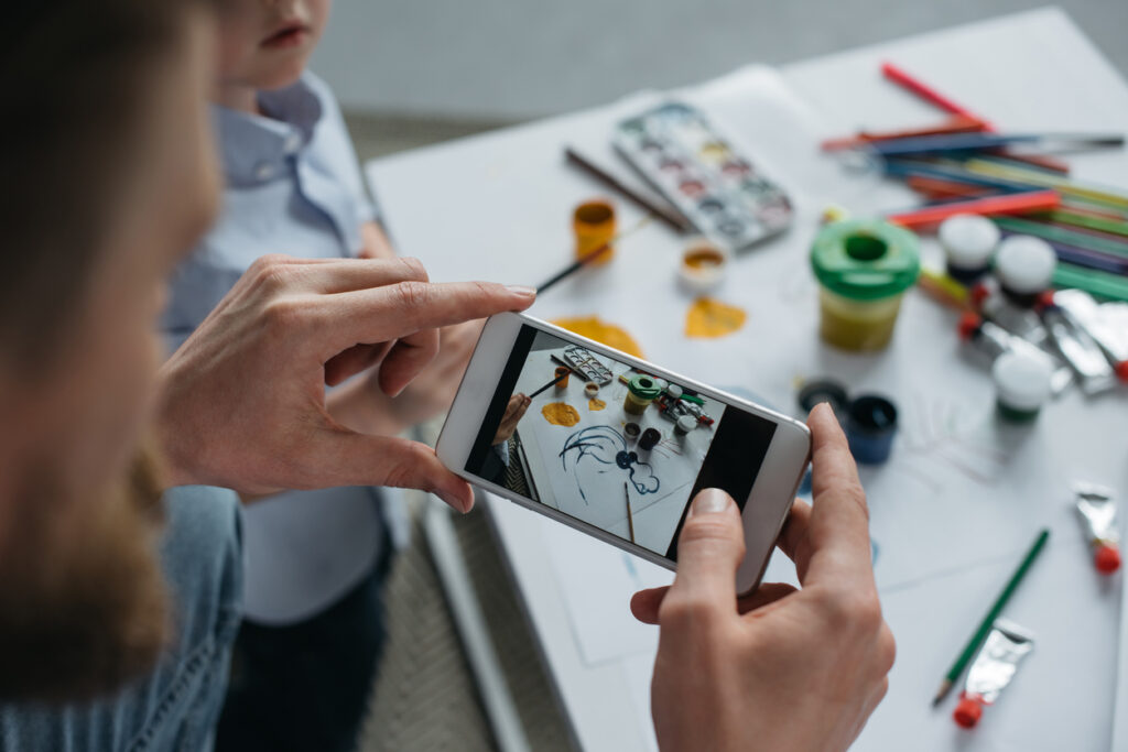 National Get Organized Month. Father taking photos of child artwork to save in their digital photo library.