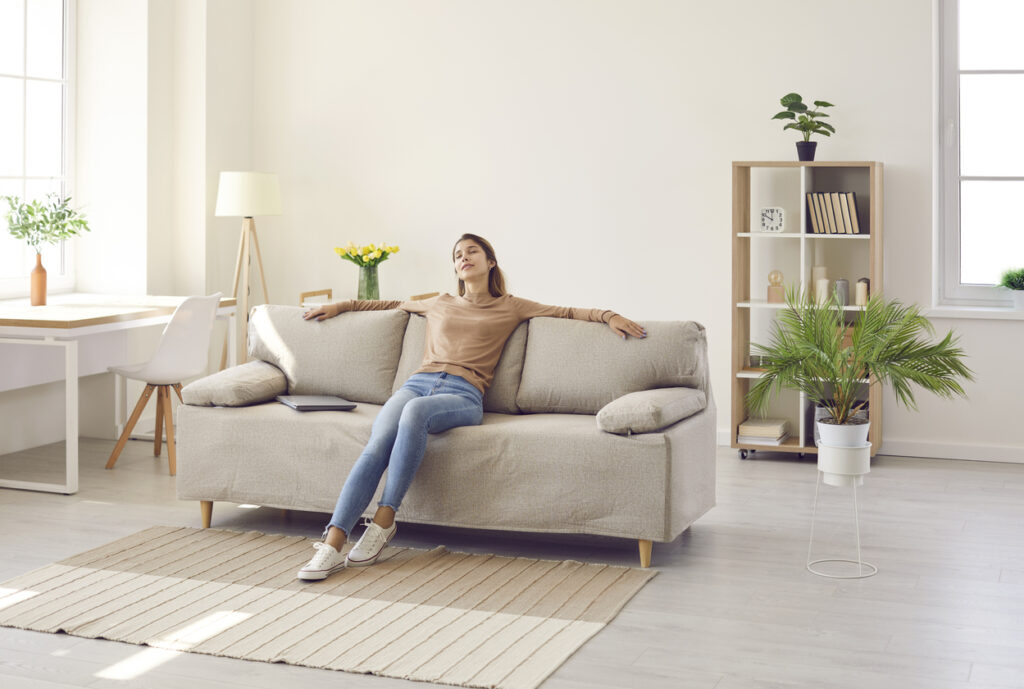 National Get Organized Month. Woman relaxing on couch after organizing home.