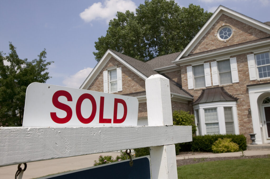 Sold house sign in suburban setting. Focus on sign.