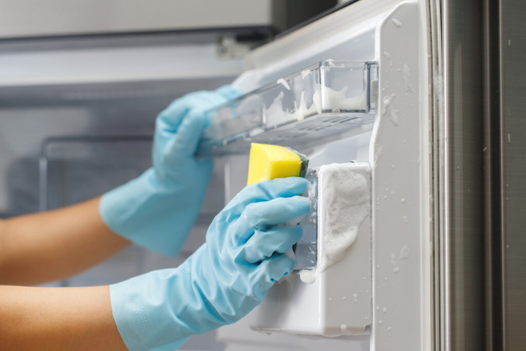 Employees use a cloth to clean the refrigerator.