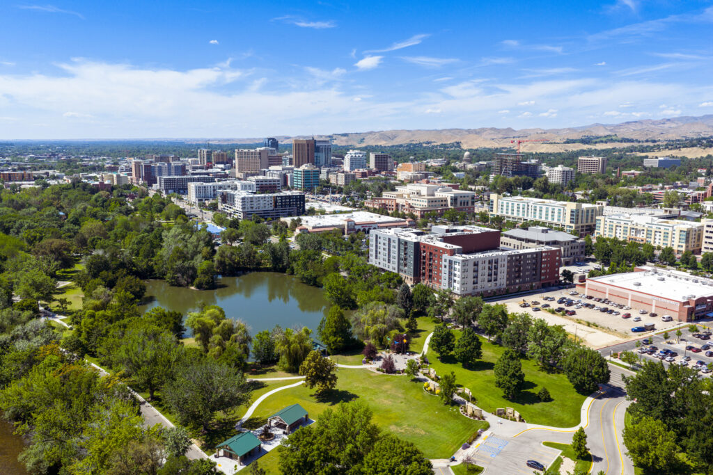 Aerial view of Boise Square Park and Julia Davis Park in downtown Boise, Idaho, with rolling foothills in the distance on a sunny day.