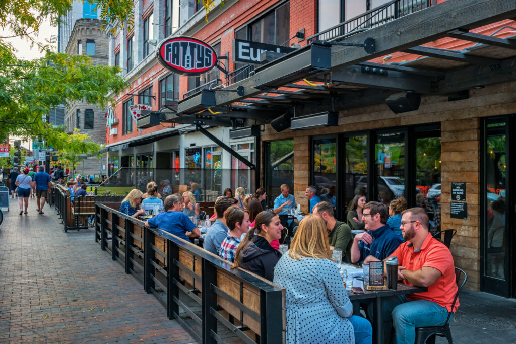 People dine at a restaurant patio in downtown Boise Idaho USA in the evening.