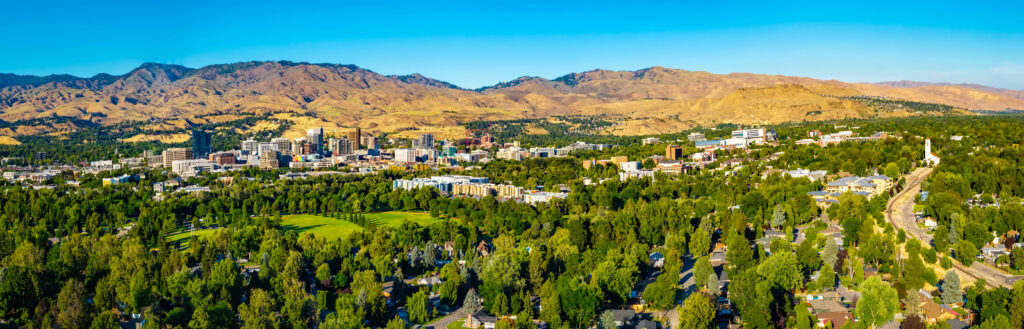 Panoramic aerial view captures Boise downtown skyscrapers illuminated by golden sunset light